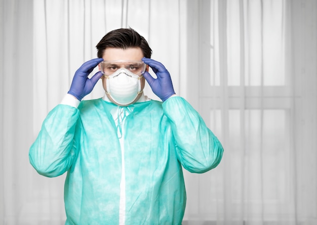 Medico stanco in equipaggiamento protettivo a casa indossa maschera medica protettiva con occhiali, epidemia di coronavirus