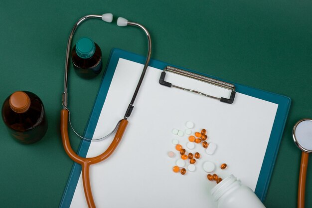 Medico sul posto di lavoro pillole dello stetoscopio arancione bottiglie mediche e appunti vuoti su sfondo di carta