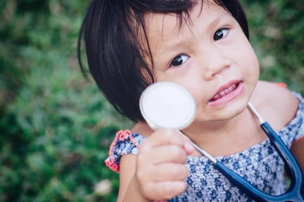 Medico sveglio della bambina con le cuffie mediche