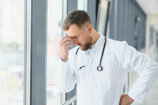 Medico triste appoggiato al muro nel corridoio dell'ospedale