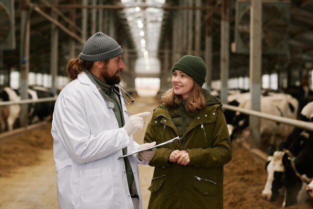 Medico veterinario che parla con il proprietario dell'azienda agricola