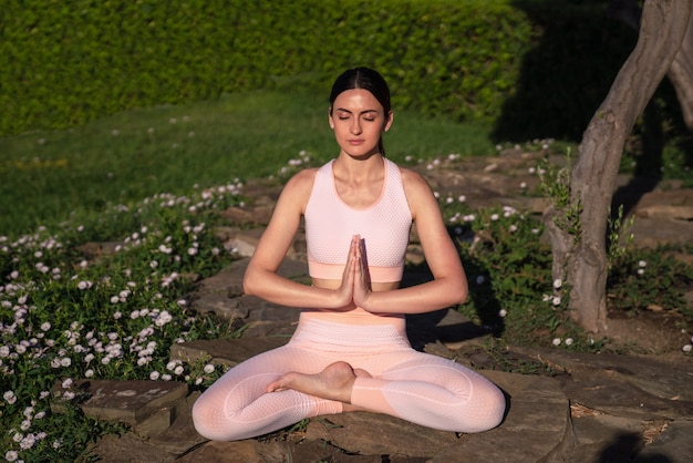 Medita nella natura. Una ragazza è impegnata nello yoga per strada, in una tuta rosa fa vari esercizi e pose yoga