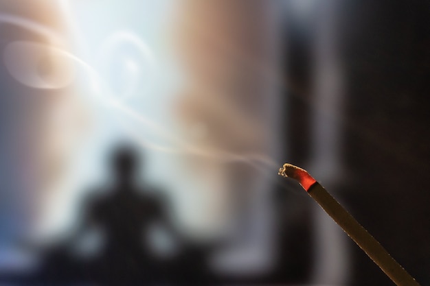 Meditando nella posizione del loto. Concentrati sul bastoncino di incenso e sul fumo. Praticante yoga irriconoscibile nel.