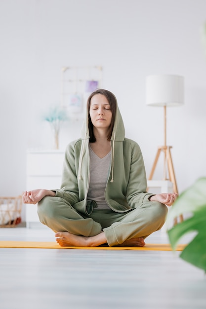 Meditazione e yoga a casa bella e giovane donna europea che fa yoga