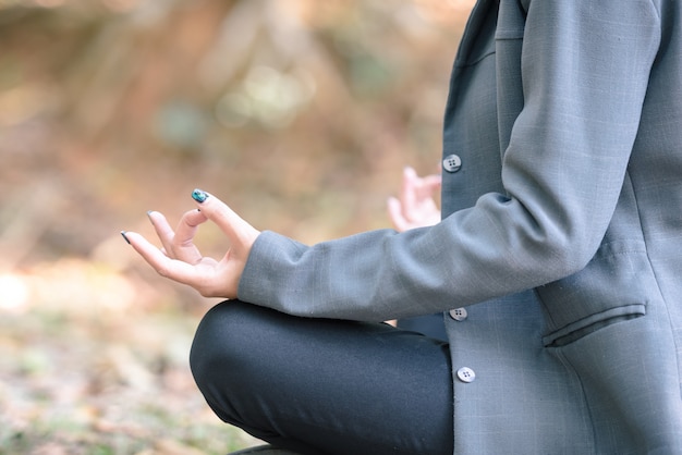 Meditazione yoga della donna d&#39;affari nel parco naturale.