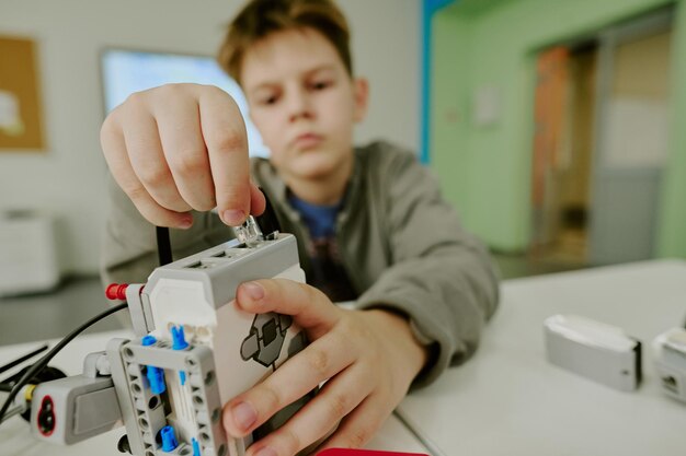 Medium close-up di ragazzi che collegano a mano i fili al robot durante la lezione di robotica