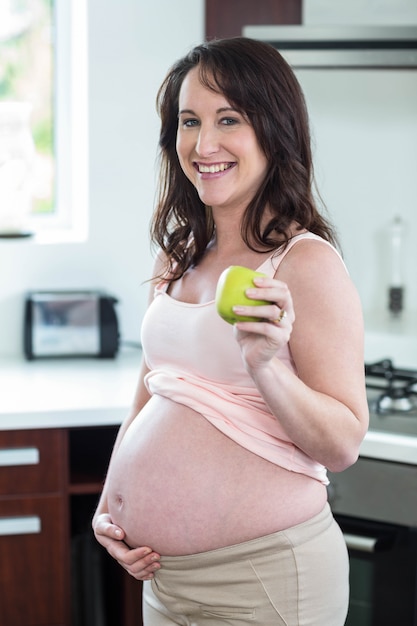 Mela della holding della donna incinta in cucina