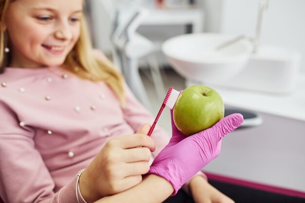 Mela di pulizia con il dente Bambina che visita il dentista in clinica Concezione della stomatologia