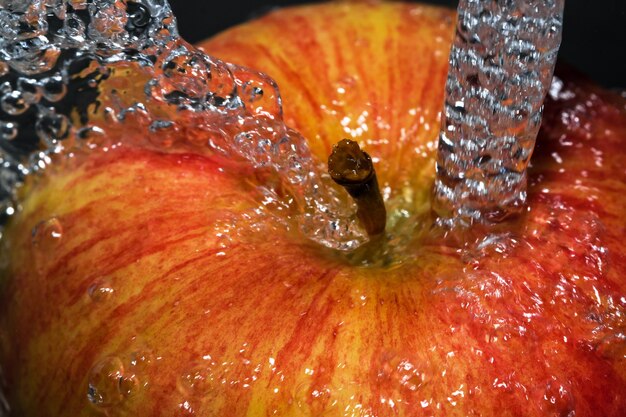 Mela dolce matura rossa sotto un flusso di acqua pulita vicino alla macrofotografia