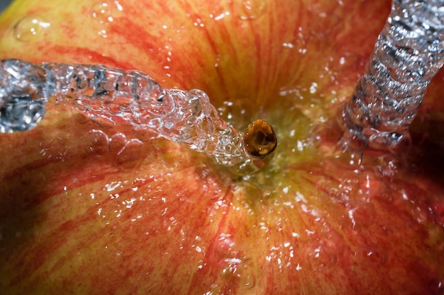 Mela dolce matura rossa sotto un flusso di acqua pulita vicino alla macrofotografia