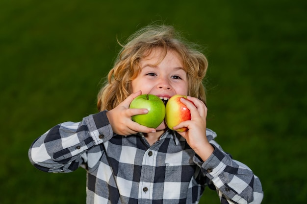 Mela fresca per i bambini kid godetevi la raccolta della mela bambino morsicato mela all'aperto in estate erba verde backgr