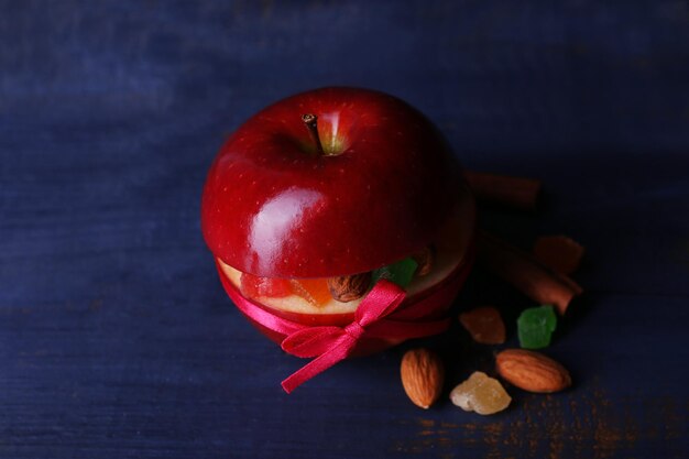 Mela rossa farcita con frutta secca con cannella e mandorla su fondo di legno colorato