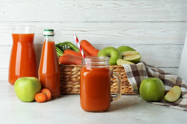 Mela - succo di carota e ingredienti sulla tabella strutturata bianca