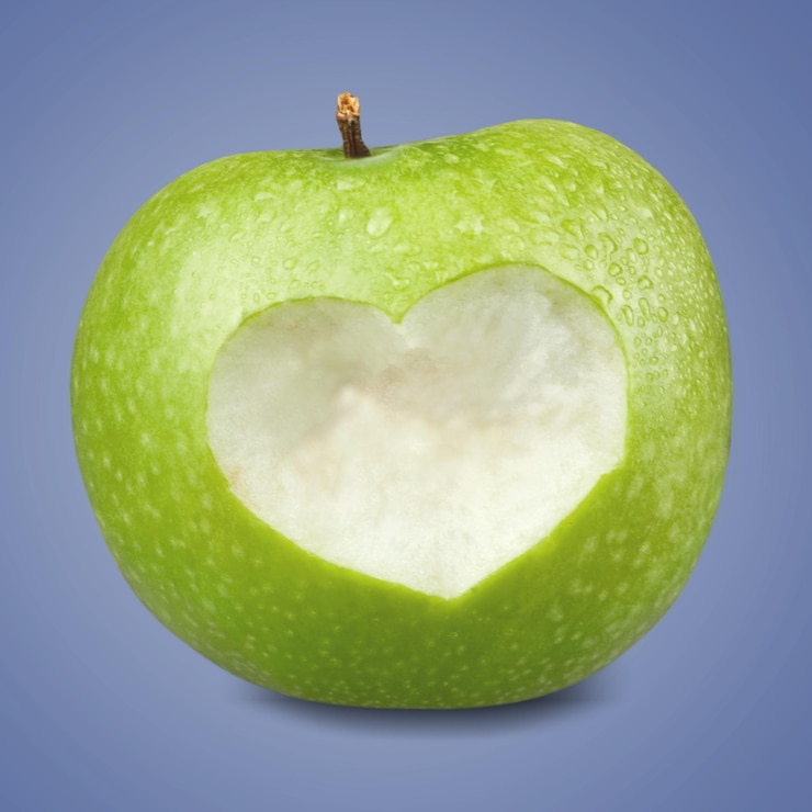Foto mela verde con un ritaglio a forma di cuore su sfondo