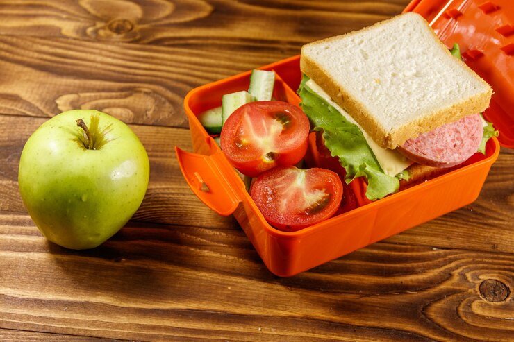 Mela verde e pranzo a scuola con panino e verdure fresche su un tavolo di legno