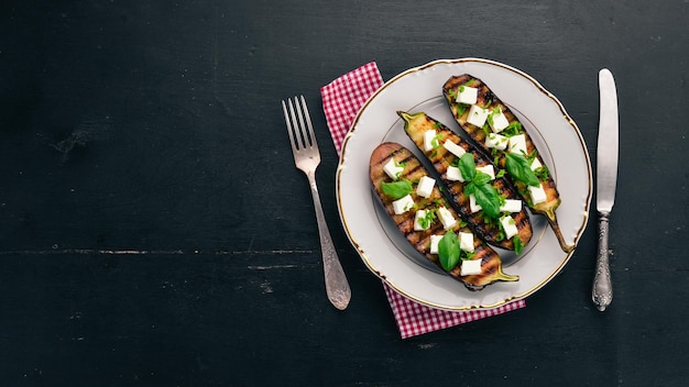 Melanzane alla griglia con formaggio feta e basilico Cibo sano Su un tavolo di legno nero Vista dall'alto Spazio libero per il testo