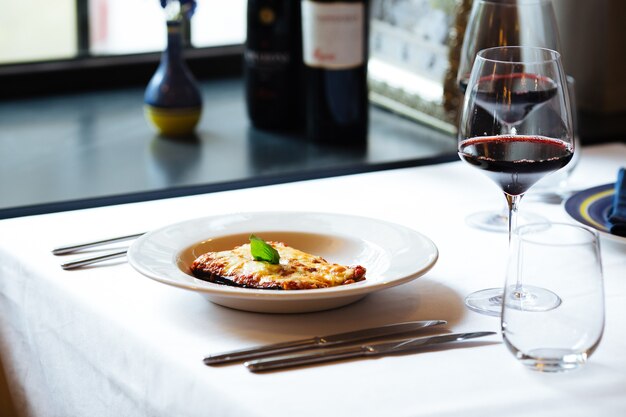 Melanzane alla parmigiana italiana con un bicchiere di vino rosso