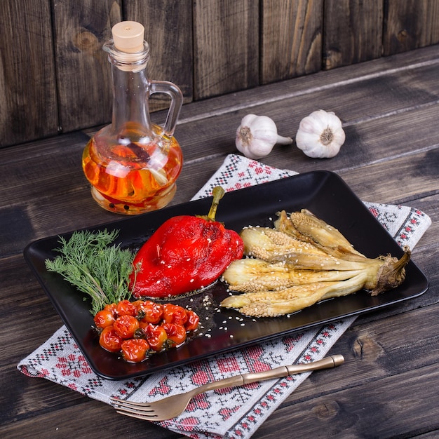 Melanzane e peperoni di verdure arrostite con pomodoro in piatto nero da vicino