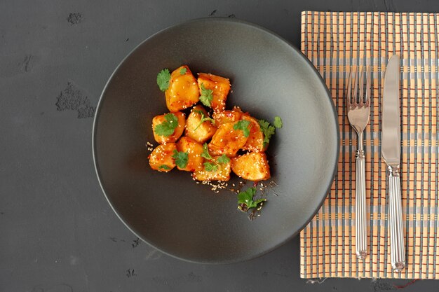 Melanzane fritte con erbe aromatiche e sesamo in vista dall'alto di ciotola di ceramica nera