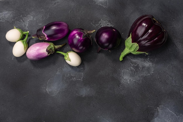 Melanzane o melanzane di diverse forme e colori su sfondo grigio scuro vista dall'alto copia spazio