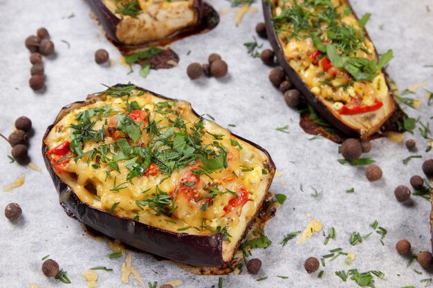 Melanzane ripiene al forno. Melanzane al forno su pergamena con formaggio, pomodoro ed erbe aromatiche