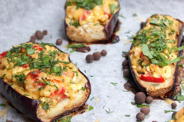 Melanzane ripiene al forno. Melanzane al forno su pergamena con formaggio, pomodoro ed erbe aromatiche