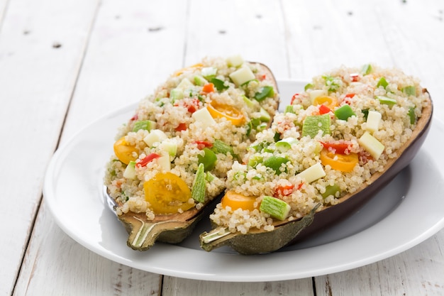 Melanzane ripiene con quinoa e verdure su fondo di legno bianco