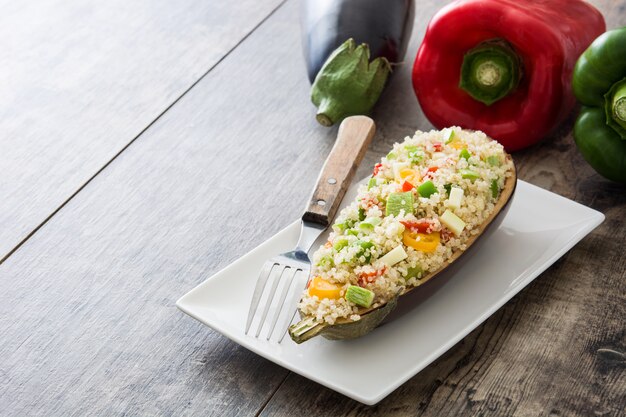 Melanzane ripiene con quinoa e verdure sul tavolo di legno