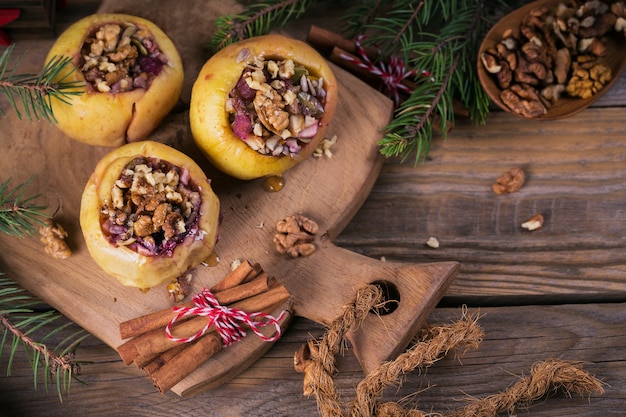 Mele al forno ripiene di frutti di bosco, noci e miele su un tagliere di legno.