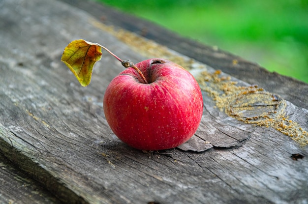 Mele autunnali mature e rosse in giardino su una vecchia tavola.