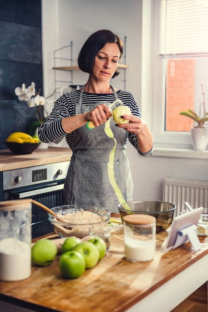 Mele della sbucciatura della donna nella cucina