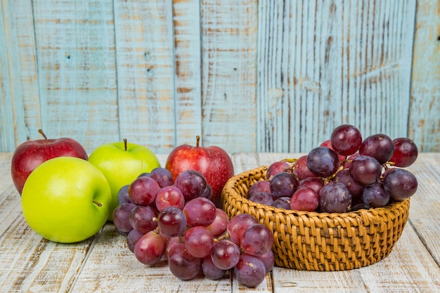 mele fresche con uva rossa su sfondo di legno