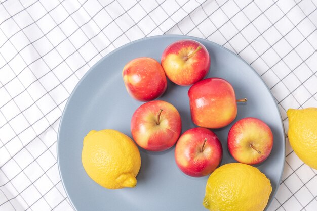 Mele fresche e limoni in un piatto sul tovagliolo controllato.