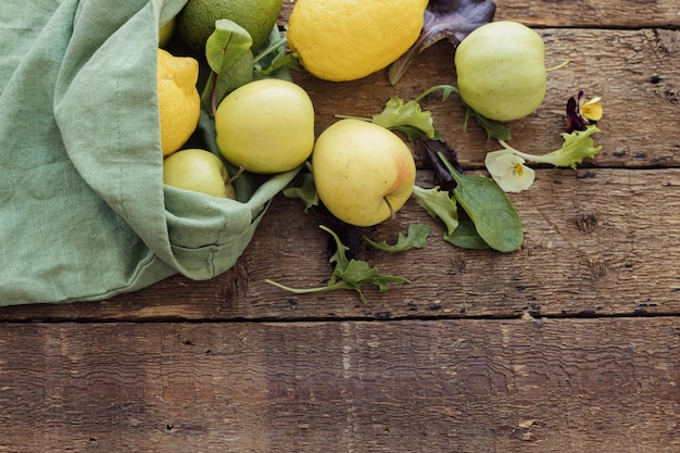 Mele fresche foglie di insalata di avocado e limone sparse da un sacchetto di cotone ecologico su legno rustico Rifiuti zero