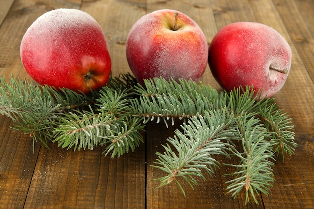 Mele glassate rosse con il ramo di abete su fondo di legno