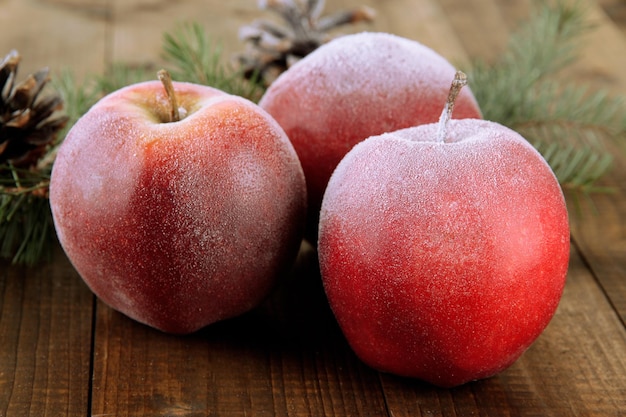 Mele glassate rosse con ramo di abete e protuberanze su fondo di legno