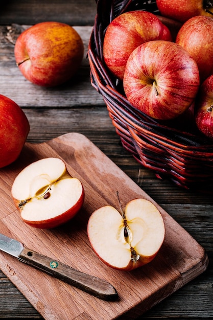 Mele mature rosse in un cestino su un fondo rustico di legno