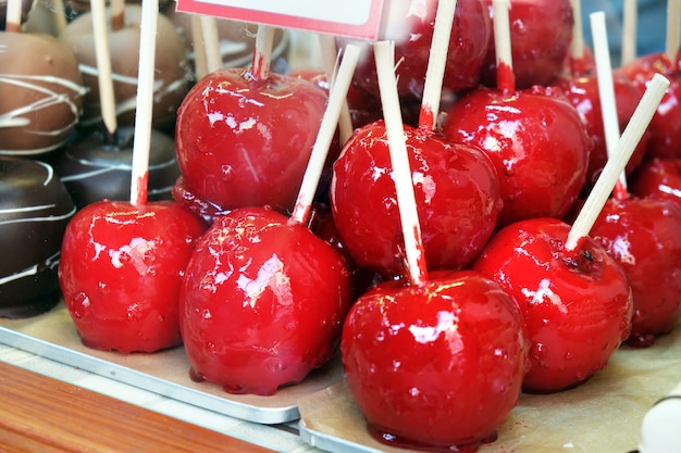 Mele ricoperte di glassa rossa nella vetrina di un negozio di caramelle. Frutta caramellata glassata, dolcetti di festa per i bambini.