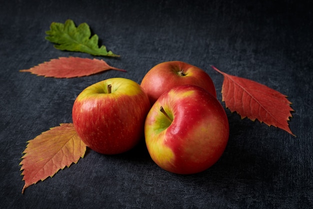 Mele rosse e foglie di autunno cadute sul tavolo scuro