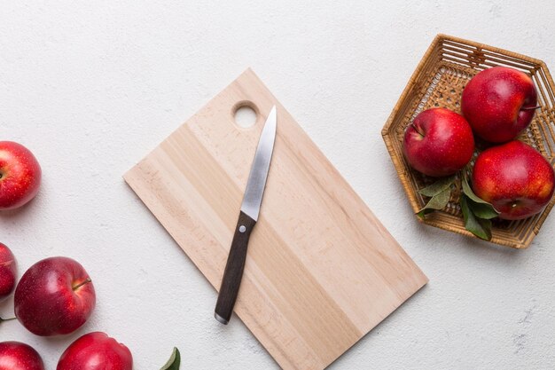 Mele rosse fresche con foglie verdi su una tavola da taglio con un coltello