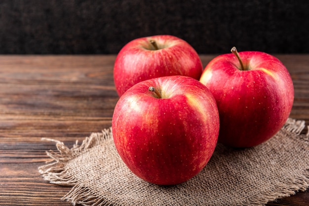 Mele rosse su superficie di legno scuro.