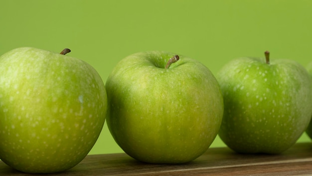 Mele verdi e fresche su fondo di legno e su colore verde