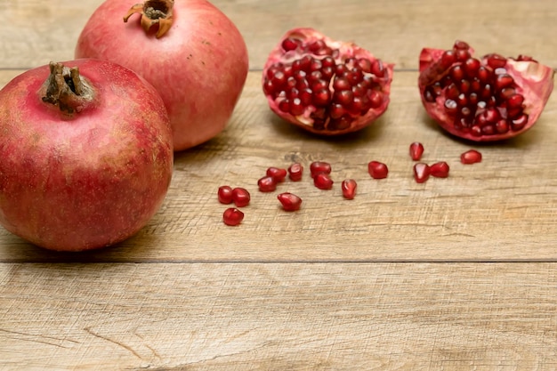 Melograni e semi succosi maturi freschi che si trovano sul tavolo. Fondo di legno rustico con lo spazio della copia. Concetto di cibo vegetariano vegano di frutti sani.