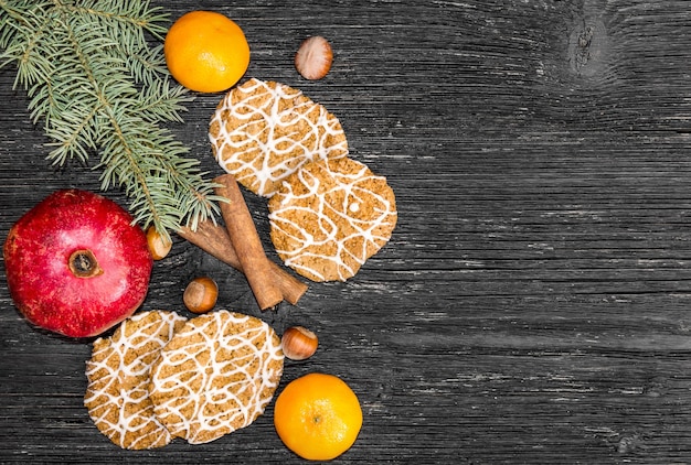 Melograno con biscotti, cannella, mandarino e ramo di albero di natale sul tabke. Decorazione natalizia.