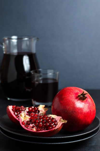 Melograno, succo di melograno in una tazza di vetro. Sfondo scuro Vista laterale. Copia spazio