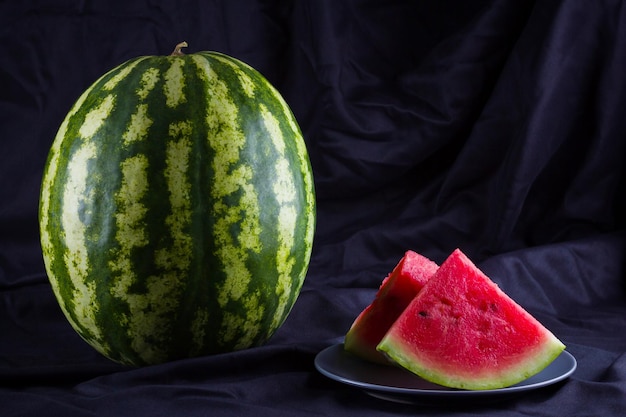 Melona d'acqua su tessuto nero Melona dacqua intera su sfondo scuro Alimento sano per vegani Copia spazio
