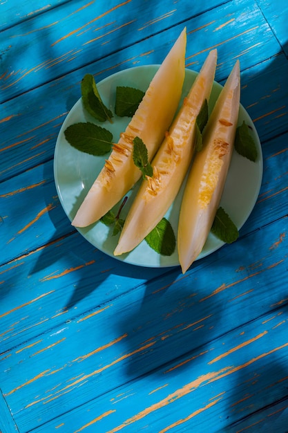 Melone appetitoso succoso maturo su un tavolo blu in una calda giornata estiva. Spuntino biologico leggero, dessert vegetariano, cibo sano