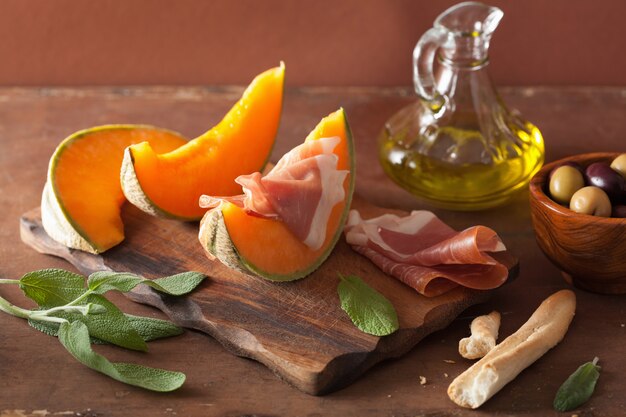 Melone cantalupo con olive di prosciutto grissini. antipasto italiano