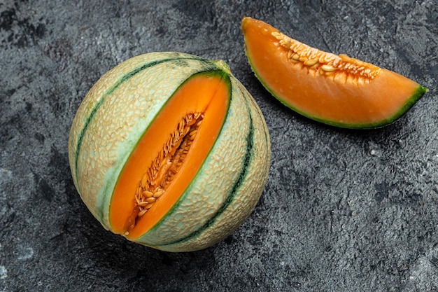 Melone cantalupo intero e fetta di melone giapponese melone arancione con semi su sfondo scuro posto per testo vista dall'alto