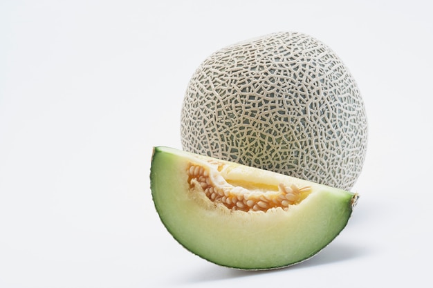 Melone fresco del cantalupo di Hami con le fette isolate su fondo bianco.